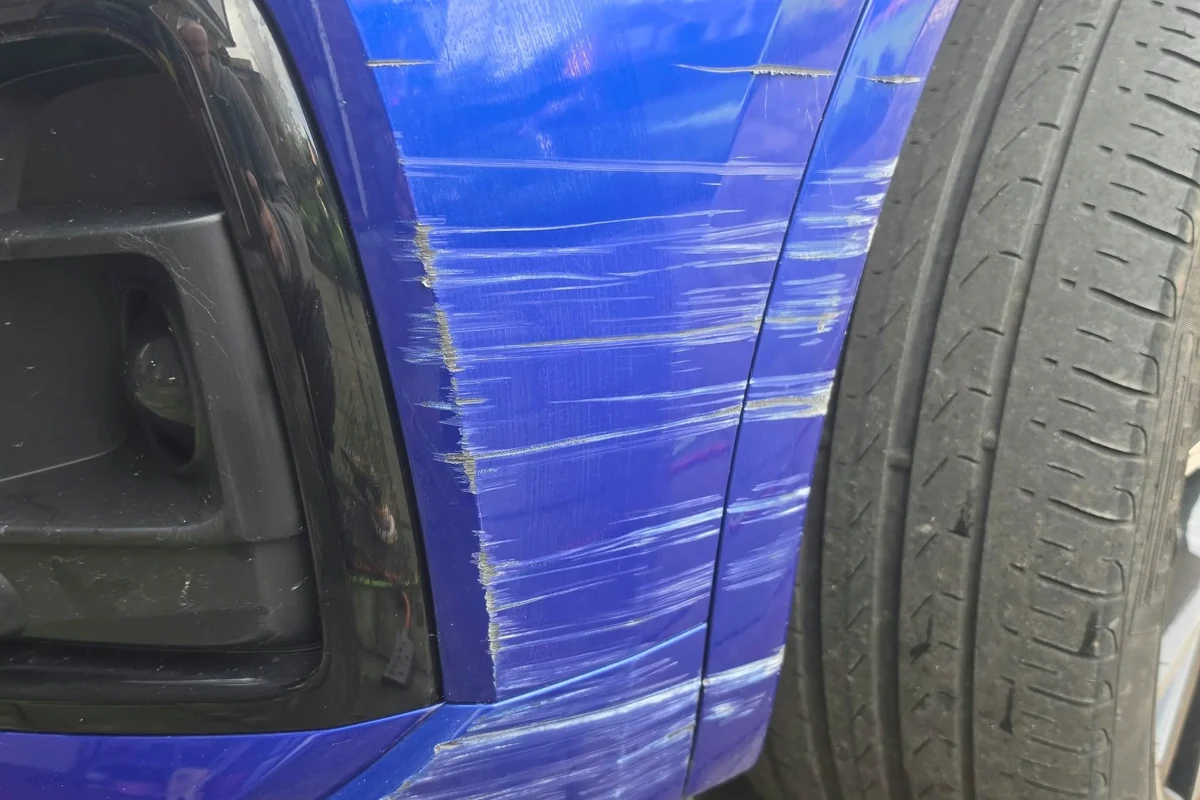 Blue car bumper with extensive white scuffs and scratches