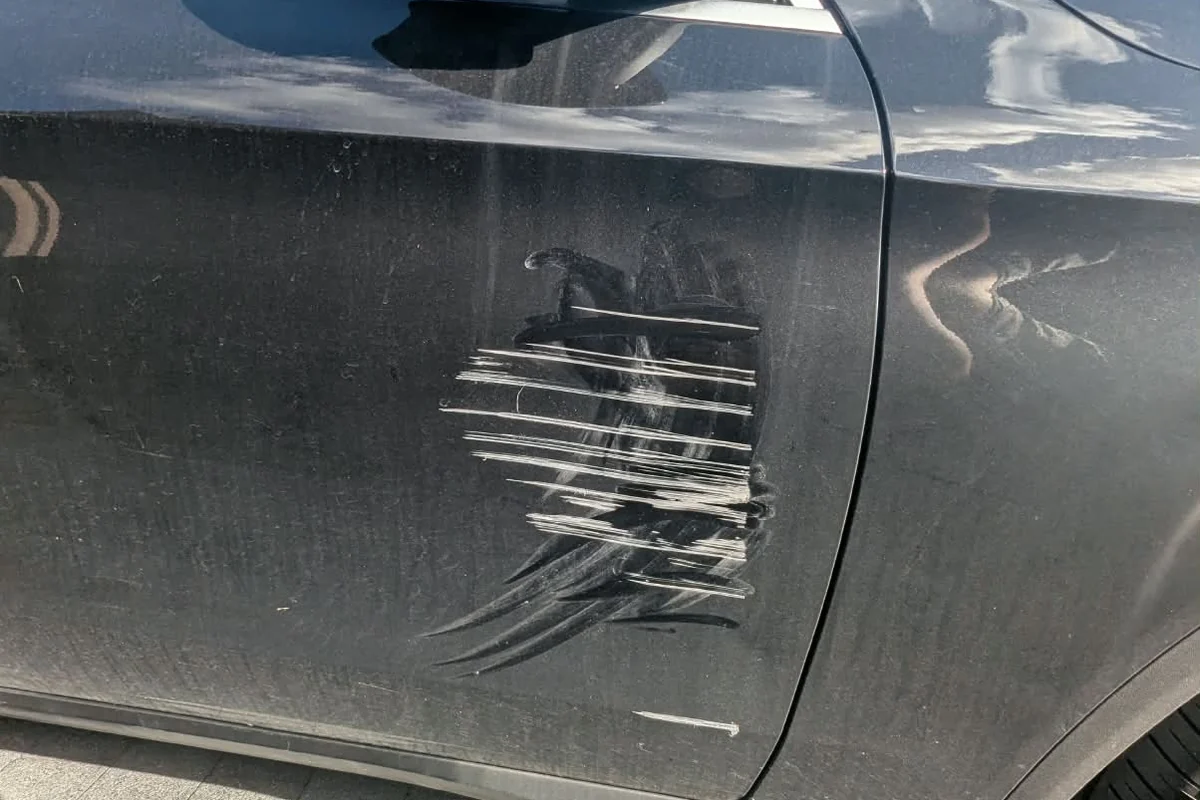 White scratch and scuff damage across a black car door